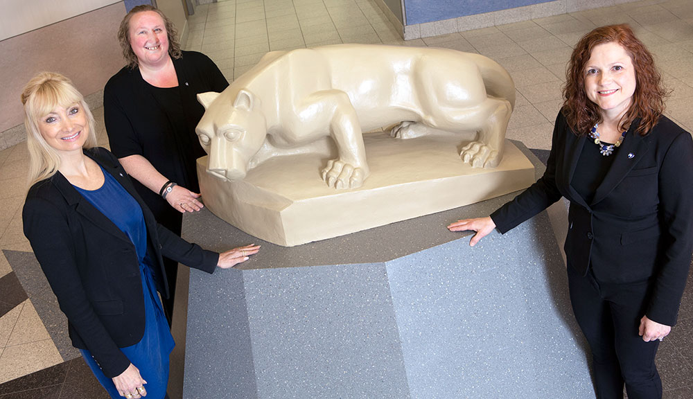 A photo of the Corporate and Foundation Relations team from Penn State College of Medicine shows three women surrounding an indoor statue of the Penn State Nittany Lion.