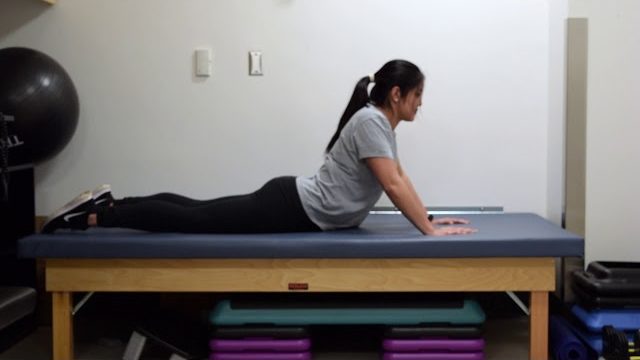 A still from a video shows a person performing the Cobra Stretch exercise.