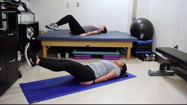 A still from a video shows two people performing the Leg Raises exercise.