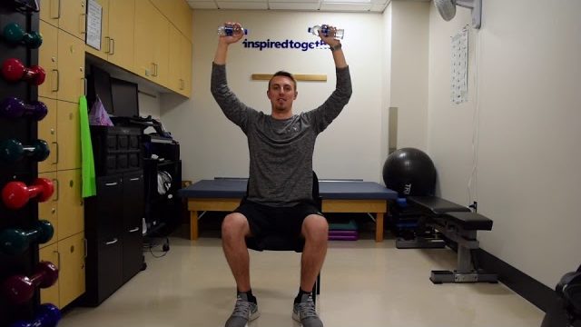 A still from a video shows a person performing the Overhead Press exercise.