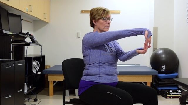 A still from a video shows a person performing the Wrist Stretch exercise.