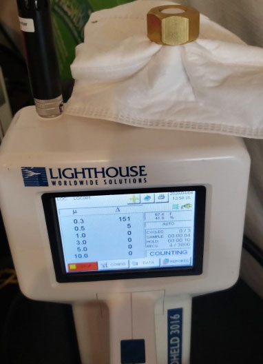 A Lighthouse 3016 Particle Counter device is seen in a room, performing particle measurements.