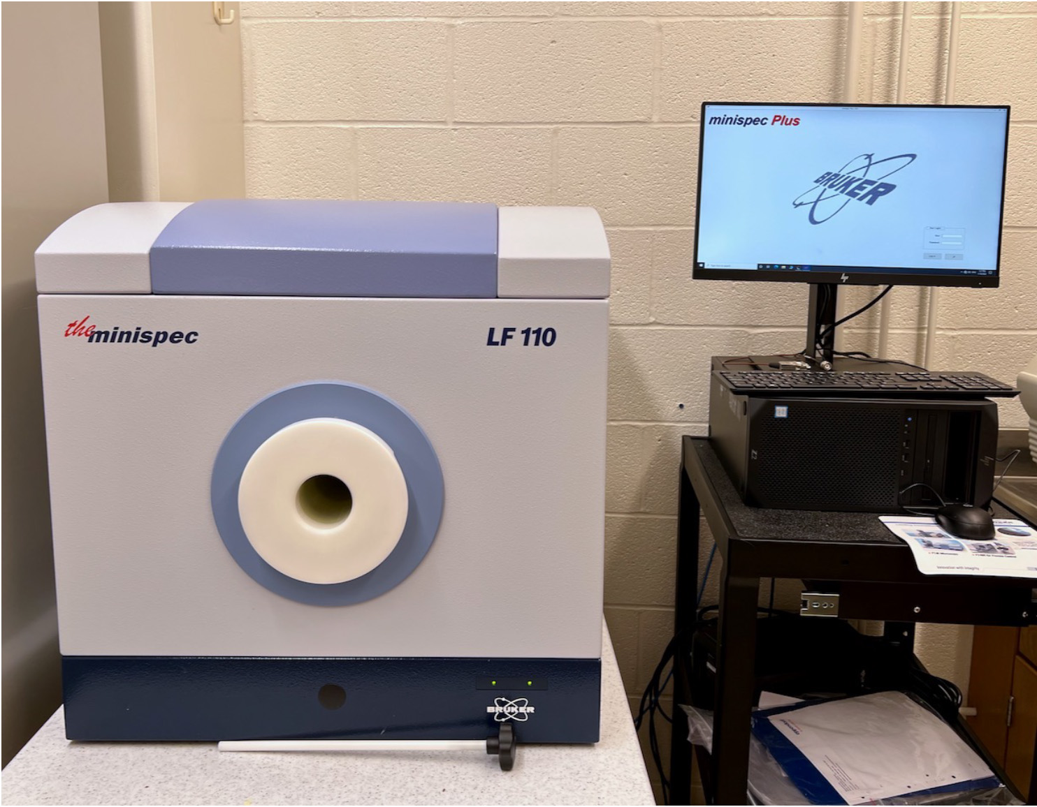 Bruker LF100 Minispec machine, a gray cube with a circle in the middle, with a computer screen to the right.