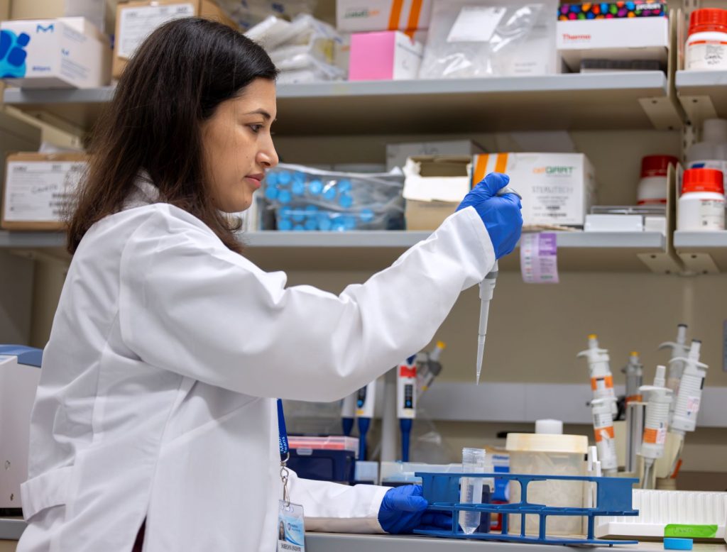 Shubekshya Upadhyay holds a dropper above a bench with other research tools in Dr. James Connor's lab