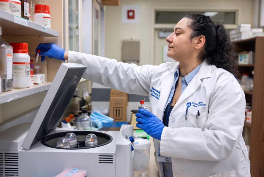 Gabriele Remite-Berthet reaches for an item with equipment on a lab bench in front of her