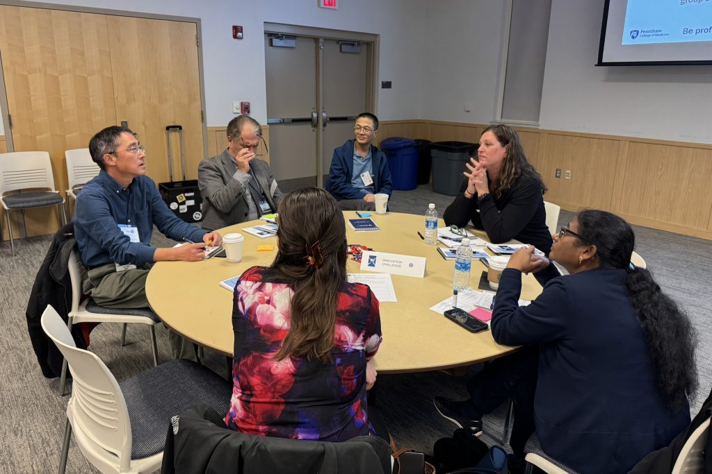 Six people seated around a round table, talking.